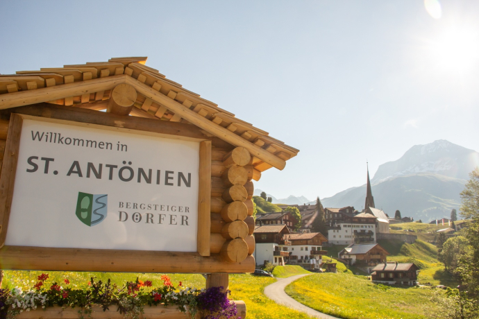 Plaque of the mountaineering village of St. Antönien, the village in the background Plaque of the mountaineering village of St. Antönien, the village in the background